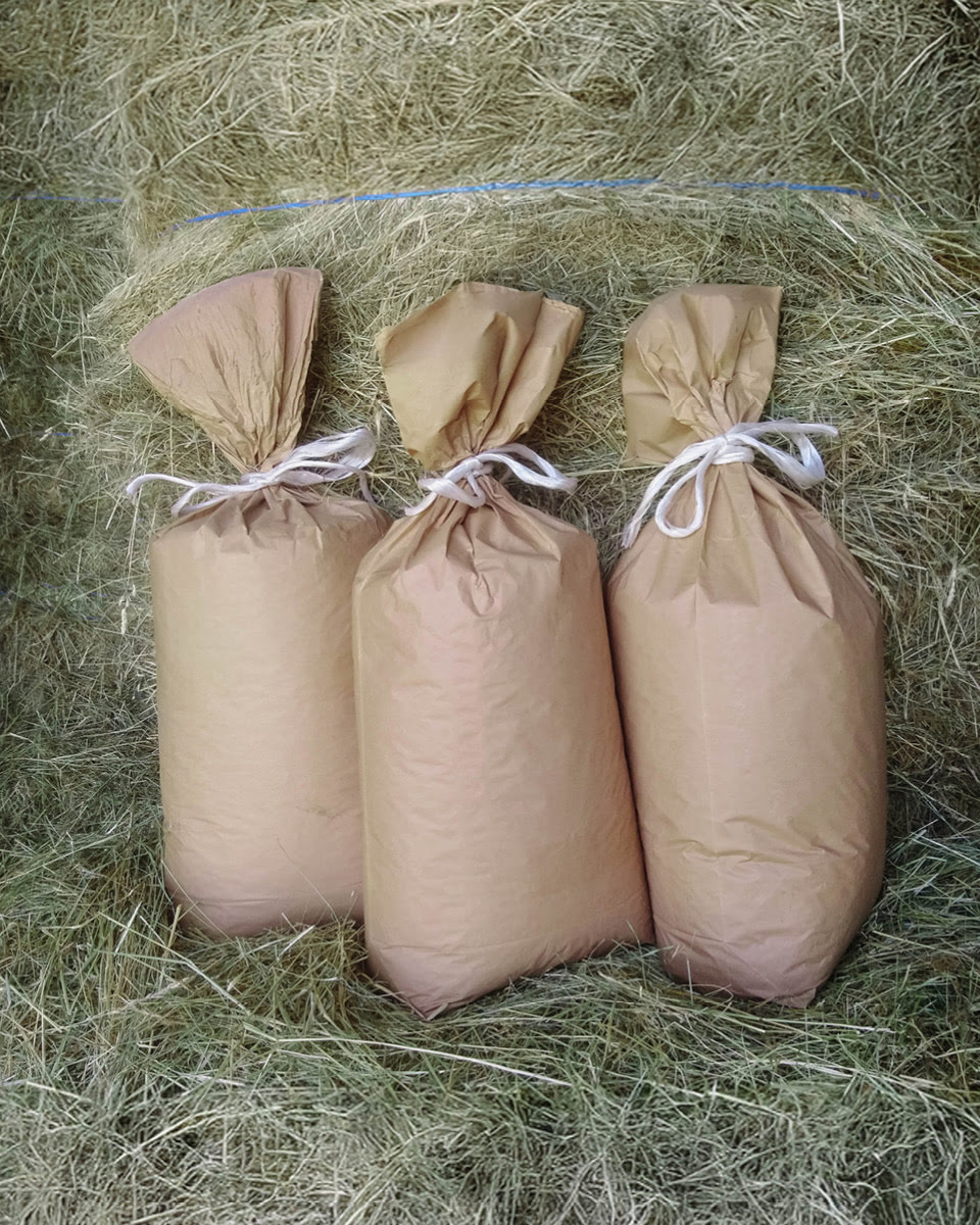 Drei Papiers&auml;cke umgeben von Heu.